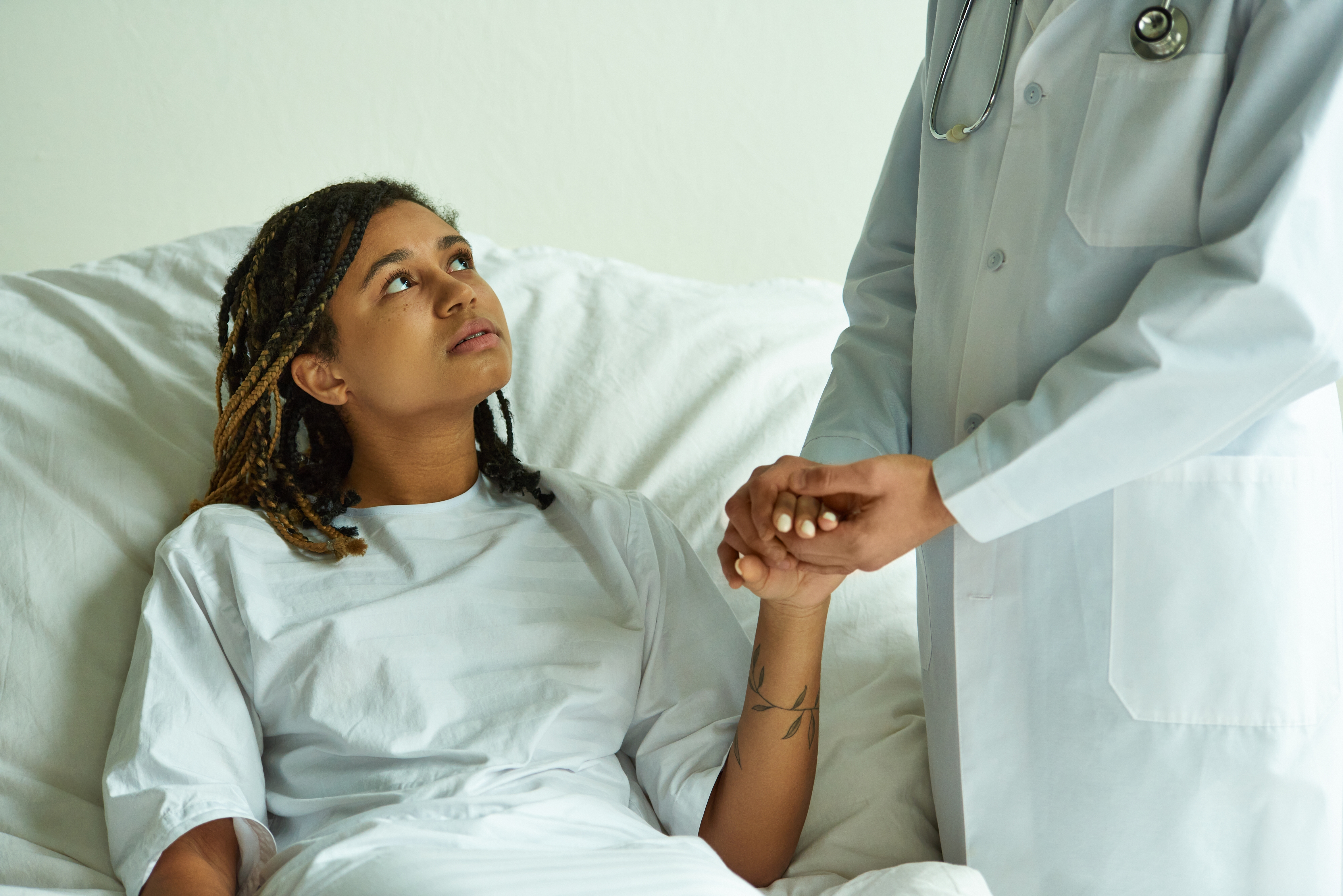 Doctor,In,White,Coat,Holding,Hand,Of,African,American,Woman,