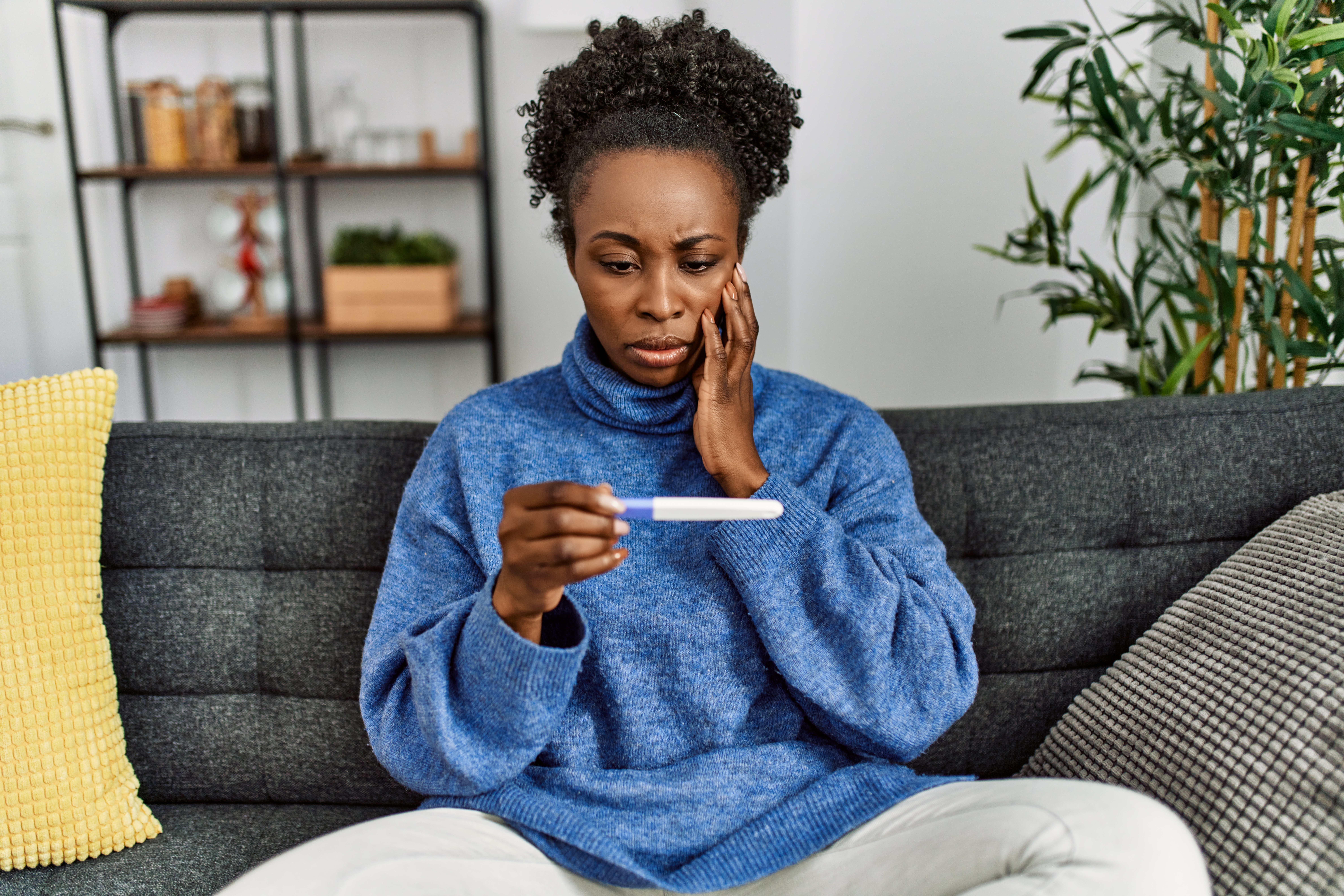 African,American,Woman,Holding,Pregnancy,Test,With,Worried,Expression,At