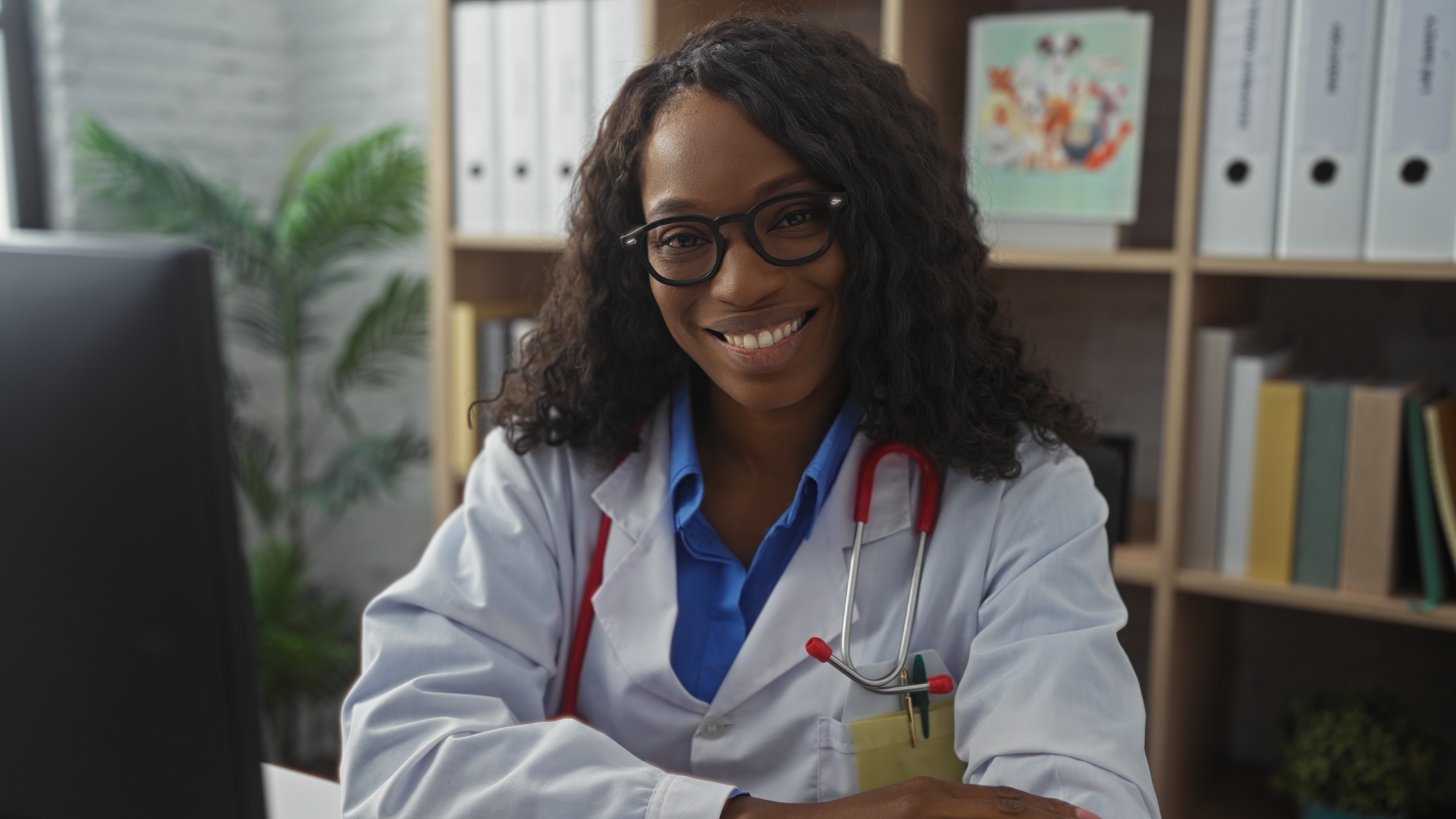 A,Smiling,African,American,Female,Doctor,With,Curly,Hair,Sits